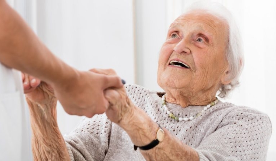 Happy Senior Patient Holding Hands Of Female Doctor In Hospital